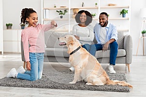 Black girl training and giving treat to her obedient dog