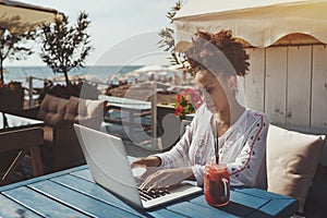 Black girl using laptop in cafe near sea