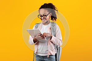 Black girl wearing backpack standing with tablet at studio