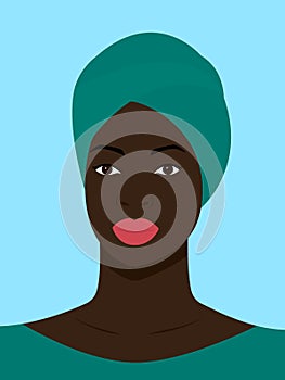 Black girl is wearing a turquoise turban. Self-confident young woman with brown skin in traditional headdress portrait front view