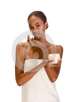 Black girl wrapped in towel putting cream on face