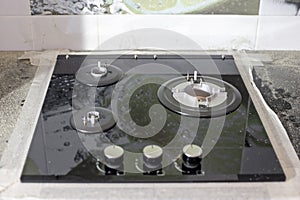 The black glass-ceramic gas hob is built into the kitchen worktop. Installation of a built-in stove