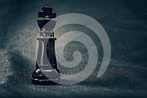 Black glass King chess piece on dramatic background