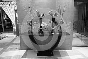 Black and Glass vases with flowers inside are put on the antique table for interior decoration in a hotel lobby. Black and White