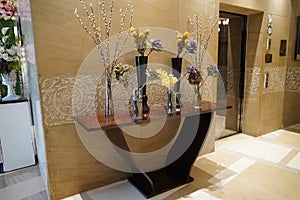 Black and Glass vases with flowers inside are put on the antique table for interior decoration in a hotel lobby. Theyâ€™re