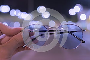 Black glasses have a male hand with a vintage bokeh background