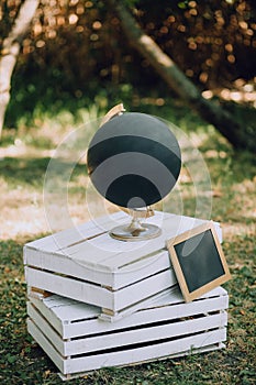 A black globe with a slate stands on wooden pallets on the grass. Wedding Original Decor