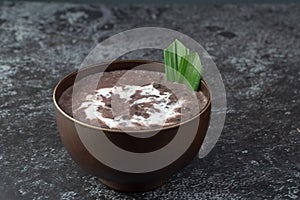 Black Glutinous Rice Porridge or Bubur Pulut Hitam in Malay with coconut milk on dark background