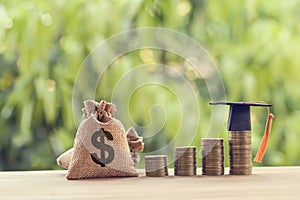 Black graduation cap, Hat and US dollar bag on rows of rising coins,  on a table. Education funding, financial concept. Depicts