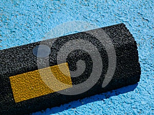 Black granular textured bumper block  bolted to asphalt pavement