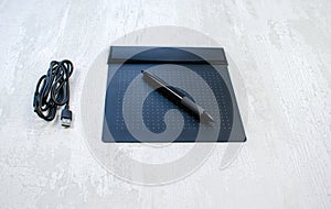 Graphic tablet with pen for illustrators and designers, isolated on a wooden background. photo