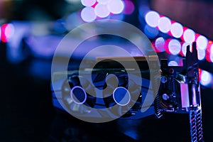 Black graphics card on black table under neon light. Part of computer for gaming and cryptocurrency mining