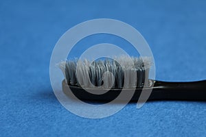Black gray old used toothbrush on a blue background side view of copy space