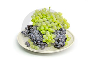 Black and green grapes bunches on white plate isolated on white