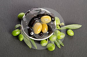 Black and green olives mixed in the porcelain bowl on gray stone