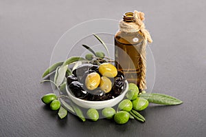 Black and green olives mixed in the porcelain bowl and Virgin olive oil