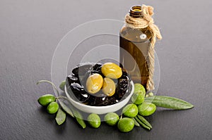 Black and green olives mixed in the porcelain bowl and Virgin olive oil