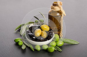 Black and green olives mixed in the porcelain bowl and Virgin olive oil