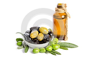 Black and green olives mixed in the porcelain bowl and Virgin olive oil in a crystal bottle on white background