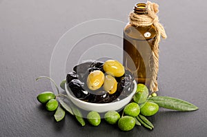 Black and green olives mixed in the porcelain bowl and Virgin olive oil