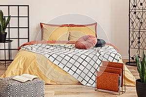 Black grille next to the bed with orange bedding in the bedroom with white walls