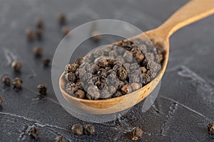 Black ground pepper in a wooden spoon