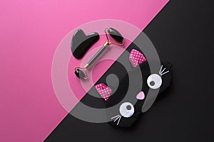 Black gua sha scraper and roller on pink and black background
