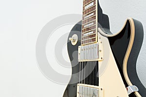 Black guitar model les paul on a white background showing part of the body