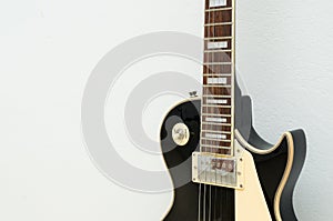 Black guitar model les paul on a white background showing part of the body