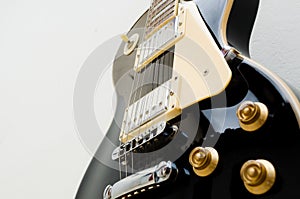 Black guitar model les paul on a white background showing part of the body in a bottom view