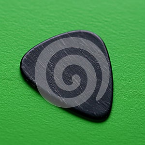 Black guitar pick with a triangular shape, featuring subtle surface texture. Positioned