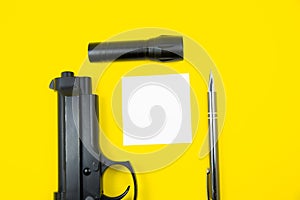 Black gun, reminder note paper, pen and flashlight lies on a yellow background. Private detectives work. Searching information