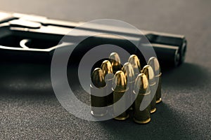 Black gun and yellow bullet on black background