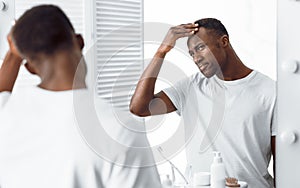 Black Guy Examining His Head Searching Gray Hair In Bathroom