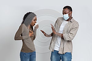 Black guy in face mask afraid of coughing woman