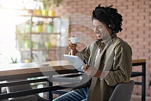 Black Guy In Headphones Relaxing With Digital Tablet And Coffee In Cafe