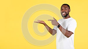 Black Guy Pointing At Hand Holding Invisible Object, Yellow Background