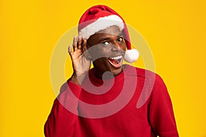 Black Guy In Santa Hat Holding Hand Near Ear Trying Overhear Something