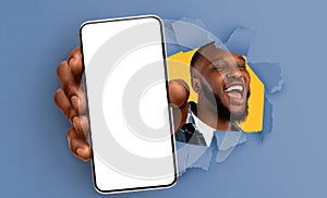 Black guy showing white empty smartphone screen through torn paper