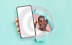 Black guy showing white empty smartphone screen through torn paper