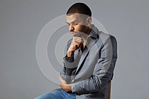 Black guy thinking in gray blazer isolated on gray background