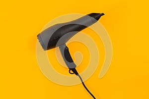 Black hair dryer on yellow paper background