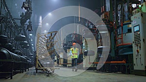 Black hair professional standing near big modern metal construction at storage.