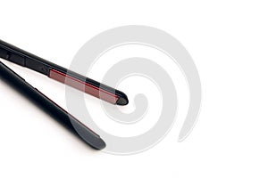 Black hair straightener isolated on white background with free space for text