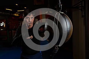 A black-haired middle-aged man in a black rashguard is engaged in boxing