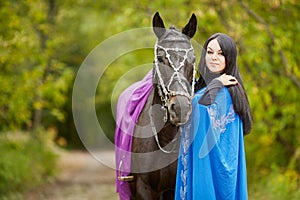 Black-haired smiling woman in blue capote stands photo