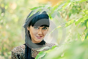 Black haired women posing in green twigs