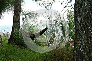 Black hammock stretched between two tress on shore of the lake Constance.