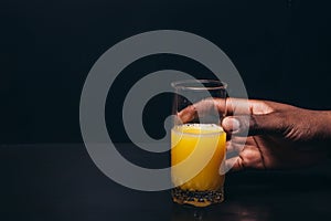 Black hand with glass of orange juice, free space