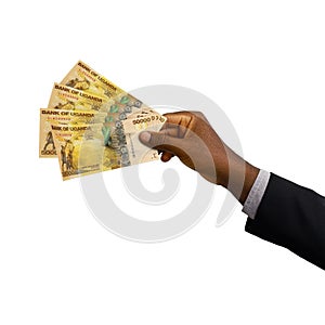Black hand with suit holding 3D rendered Ugandan Shilling notes isolated on white background